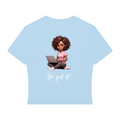 A light blue short-sleeve t-shirt with a cartoon graphic of a woman with curly brown hair sitting cross-legged and using a laptop, with the text 'Go get it!' printed below in white script.