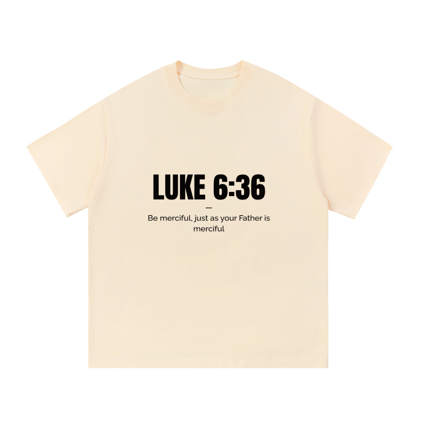 A cream-colored short-sleeve t-shirt with black printed text on the front reading 'LUKE 6:36' and 'Be merciful, just as your Father is merciful'.