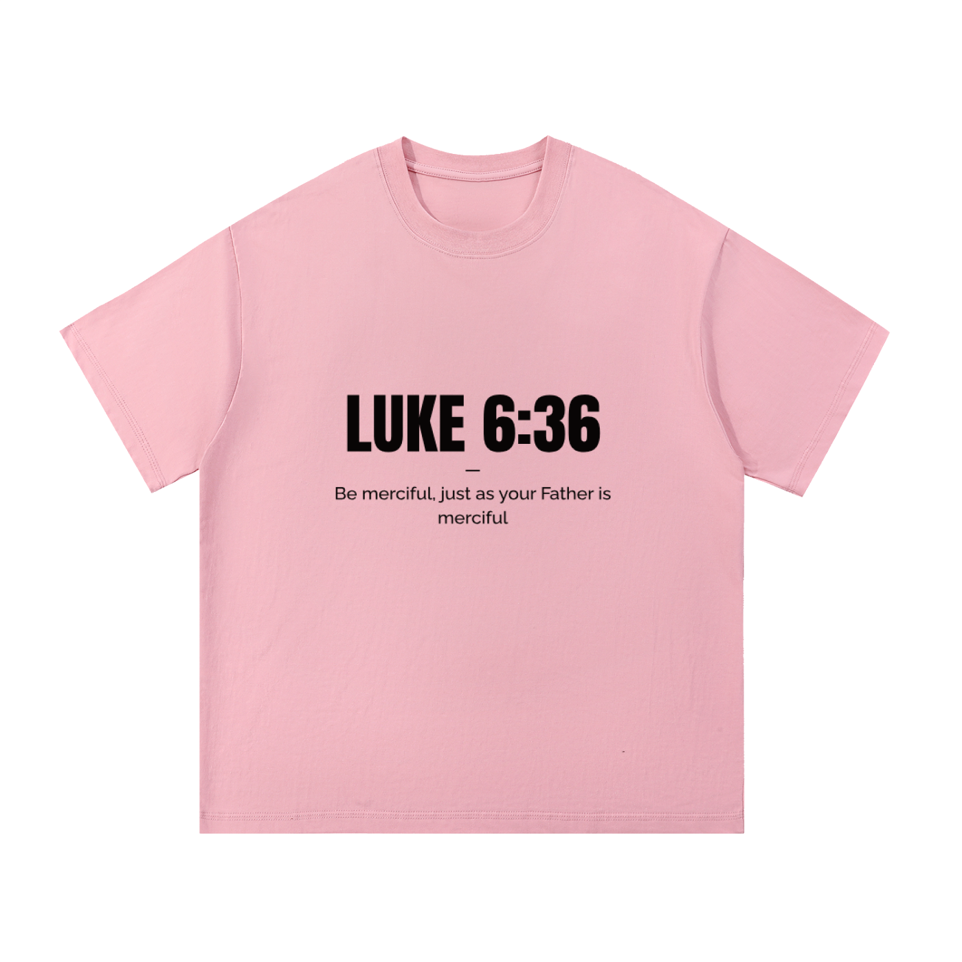 A light pink short-sleeve crewneck t-shirt with black printed text on the chest reading 'LUKE 6:36' and a quote underneath, displayed flat against a solid white background.